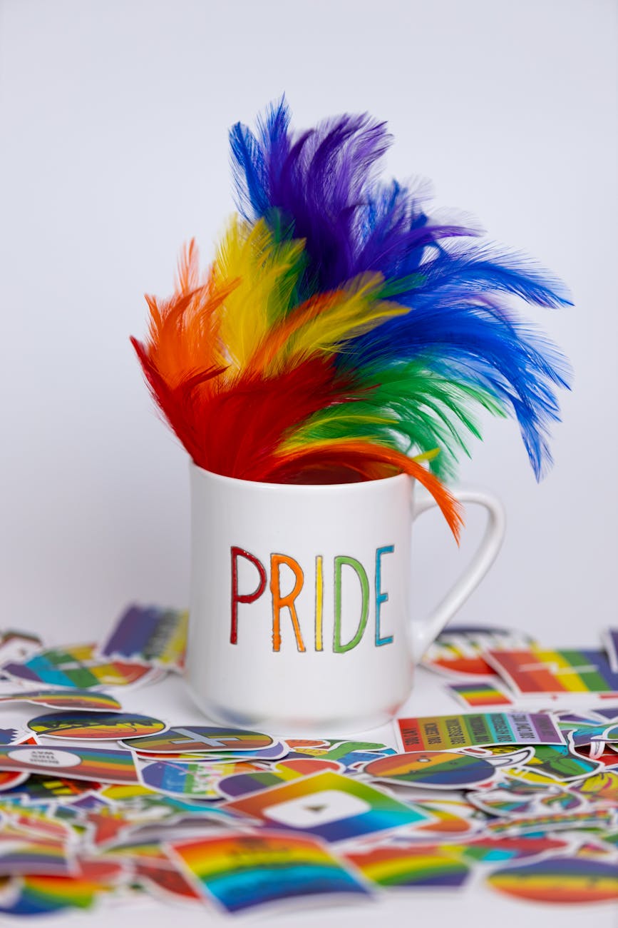 Vibrant pride-themed mug with rainbow feathers and stickers symbolizing diversity and inclusion.